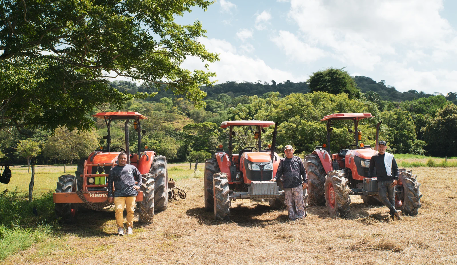 Tres personas junto a los tractores de la operación en el campo.